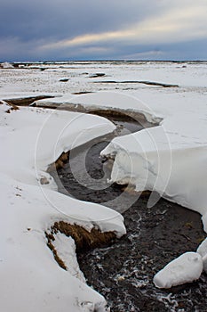 brook run in the icelandic wilderness, still covered by snow