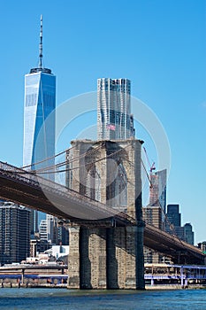 The Brooklyn Bridge with an American Flag over the East River with the Lower Manhattan New York City Skyline