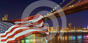 Brooklyn Bridge closeup over East River at night in New York City Manhattan and American flag flying