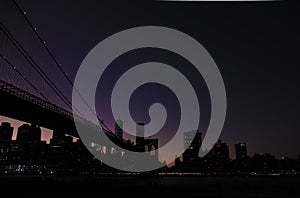 Brooklyn bridge and lower manhattan at night after sunset with colorful skies