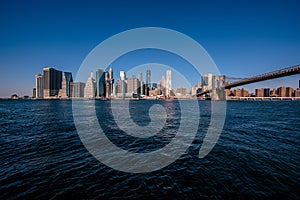 Brooklyn Bridge and the Lower Manhattan skyline panorama from Brooklyn Bridge Park riverbank, New York City, USA