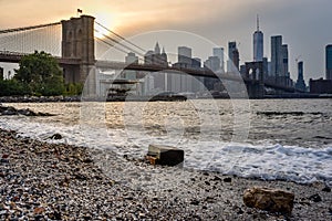 Brooklyn bridge and Manhattan skyline at dusk form Pebble Beach. NYC, USA