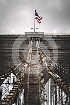 Brooklyn Bridge in New York with American Flag Waving on Top