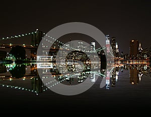 Brooklyn Bridge by night reflect in east river and new york skyline. freedom tower