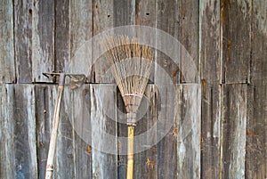 The broom is placed on an old wooden wall in rural area