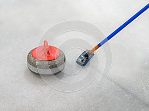 Broom and stone for curling on ice of a indoors rink.