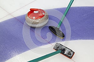 Brooms and stone for curling. view of red curling stone in outer blue ring of house with broom nearby