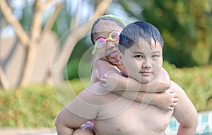 Brother holding his sister on his back in swimming pool