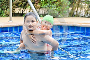 Brother holding sister on his back in swimming pool