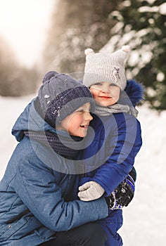 Brother hugs his little sister in nature in winter. Happy children together