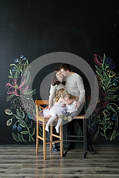 The brother kisses the sister. Mother kisses the father. Portrait of members of the family in studio.