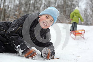 Brother lie on snow, sister pulls sleigh