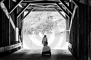 Brother Pulling Other In Wagon On Covered Bridge
