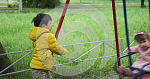 Brother pushing his little sister on swing