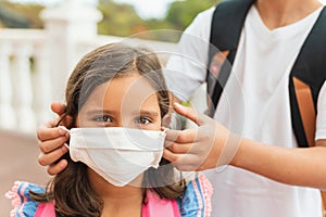 Brother puts on her sister sterile medical mask. Child, wearing face mask, protect from infection of virus, pandemic, outbreak and