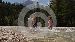 Brother and sister barefoot on on a small river in a forest walk. Family walk in a wood on a small river. Kids crossing a