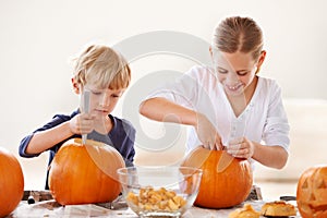 Brother and sister bonding. A brother and sister hollowing and carving pumpkins for halloween.