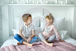 Brother and sister boy and girl play together in bedroom. Little girl look on her brother. Happy childhood in cozy family circle.