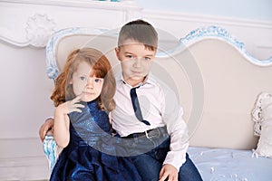 Brother and sister. Bright interior. Blue dress. Horizontally