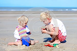 Brother and sister building sand castles on the beach