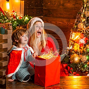 Brother and sister celebrate Christmas or New Year. Woman and the little boy are excited about something. Christmas tree