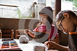 Brother and sister coloring clay handicrafts with brushes and paint