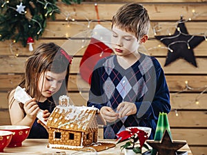 Brother and sister decorating gingerbread house