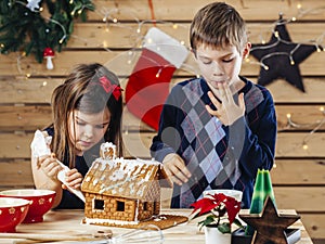 Brother and sister decorating gingerbread house