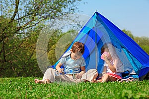 Brother and sister drinking water in tent outdoor