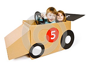 Brother and sister driving a cardboard car