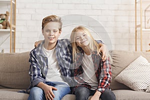 Brother And Sister Embracing Smiling Sitting On Couch At Home