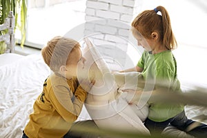 Brother and sister are fighting with pillows on the bed at home. The children had fun.