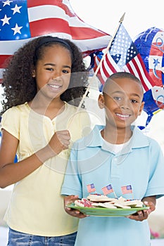 Brother and sister on fourth of July with flags