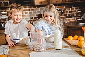 Brother and sister have corn flake rings for breakfast sitting at the table