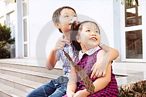 Brother and sister having fun and smiling outdoor together. Happy asian family with their children