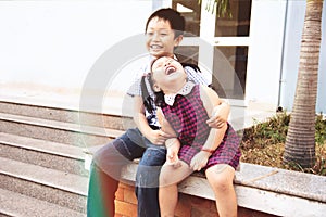 Brother and sister having fun and smiling outdoor together. Happy asian family with their children
