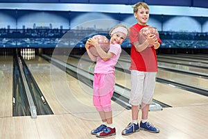 Brother and sister hold balls in bowling club