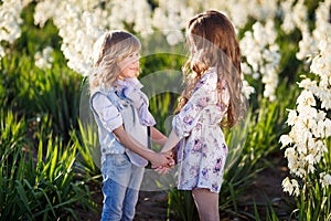 Brother and sister hugging in the field of white Yucca flowers and having fun. Family, friendship, and happiness concept