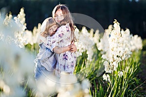 Brother and sister hugging in the field of white Yucca flowers and having fun. Family, friendship, and happiness concept
