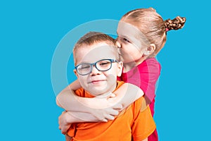 Brother and sister hugging and smiling. Isolated on a blue background