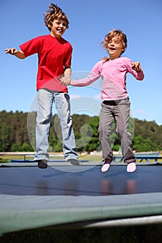 Brother and sister jump on trampoline