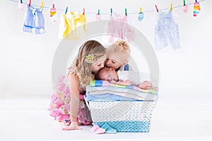 Brother and sister kissing newborn baby