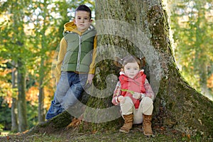 Brother and sister leaning against a tree