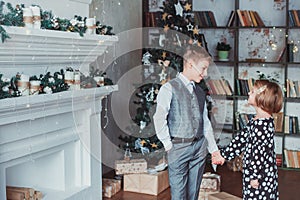 Brother and sister in the living room in the background of the Christmas tree. Children festively dressed