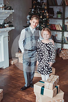 Brother and sister in the living room in the background of the Christmas tree. Children festively dressed