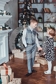 Brother and sister in the living room in the background of the Christmas tree. Children festively dressed