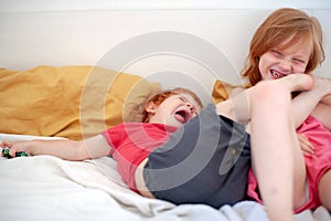 Brother and sister are lying on the bed