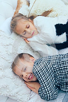 Brother and sister lying in the bed.The younger brother prevents the older sister from sleeping.