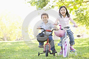 Brother and sister outdoors on bicycles smiling