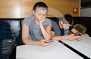 Brother and sister play with a smartphone waiting to have lunch